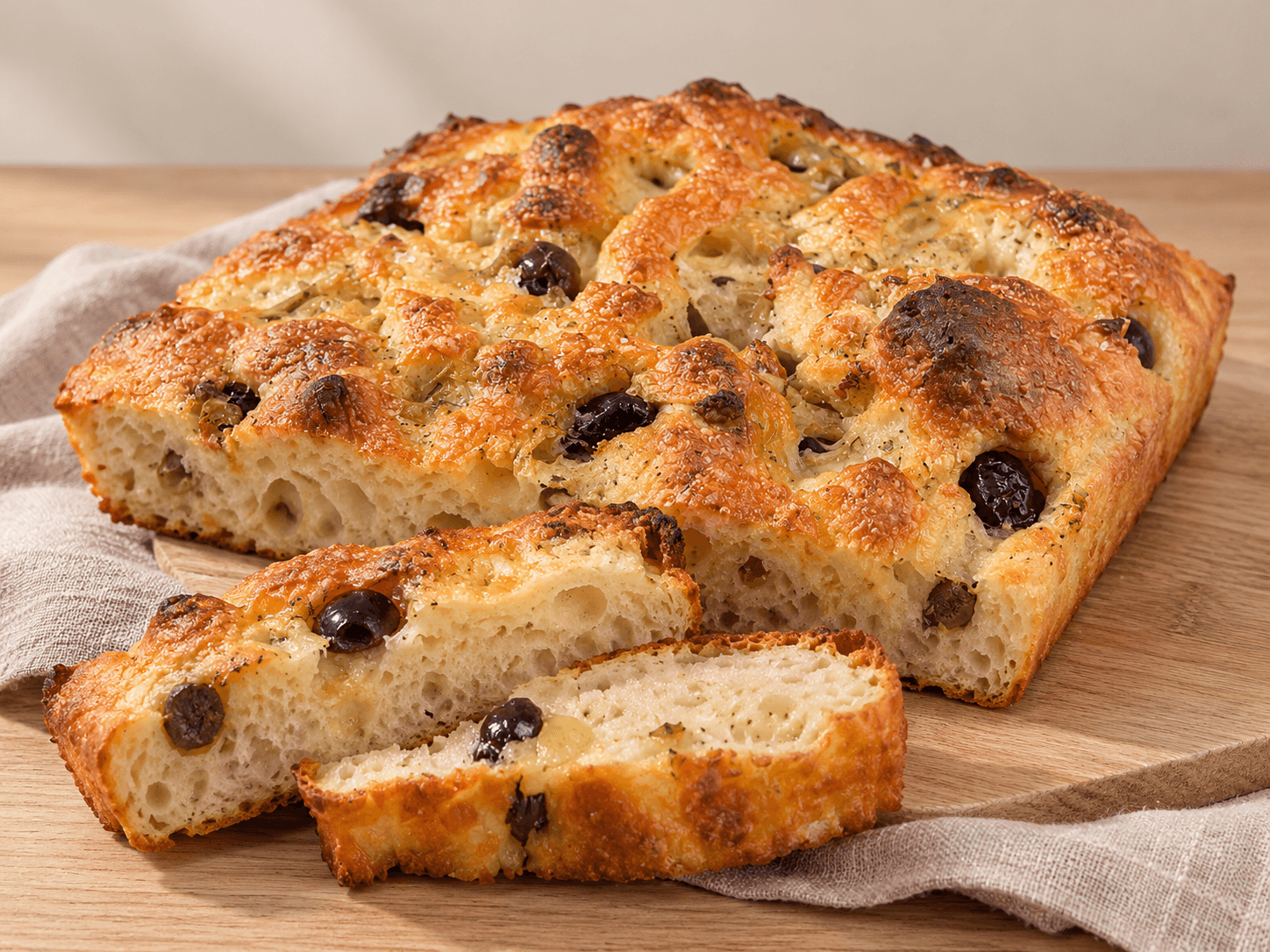 Olive focaccia with sliced pieces showing the open crumb